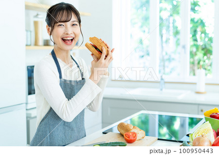 キッチンで料理をするエプロンの若い女性 キッチンで料理をするエプロンの若い女性 100950443