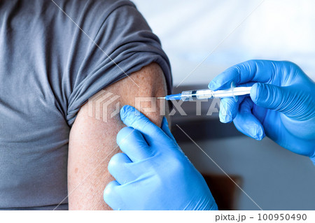 Elderly Man in Face Mask getting Covid Vaccine. Doctor giving Injection to senior Man at Hospital. Virus, COVID-2019, Flu protection. Vaccination of old Patient in Clinic during Coronavirus pandemic. 100950490