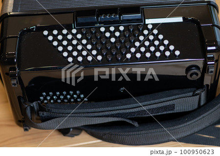 無垢板の床の上に置いてあるクロマチックボタン式アコーディオン 100950623