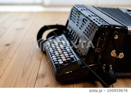 無垢板の床の上に置いてあるクロマチックボタン式アコーディオン 100950676