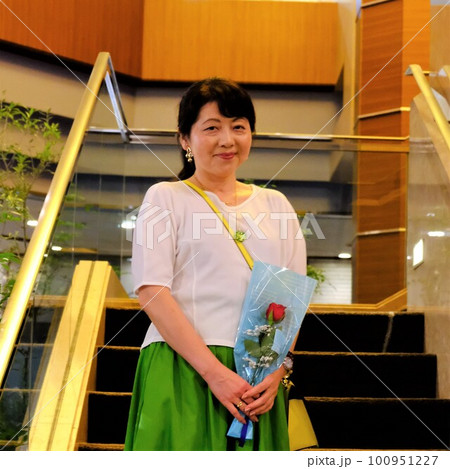 プレゼントされた花と一緒に会談で記念写真をする女性 100951227