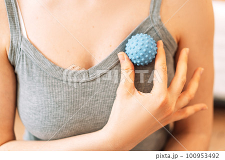 Lady kneads pectoral muscles with myofascial ball 100953492
