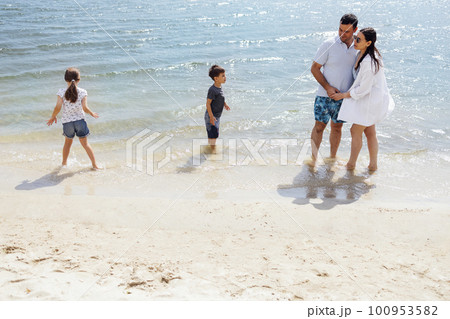 Son and daughter run on the water and splash on their smiling parents Son and daughter run on the water and splash on their smiling parents 100953582
