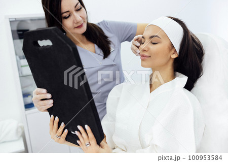 Doctor checking woman face skin in cosmetology clinic before plastic surgery Doctor checking woman face skin in cosmetology clinic before plastic surgery 100953584