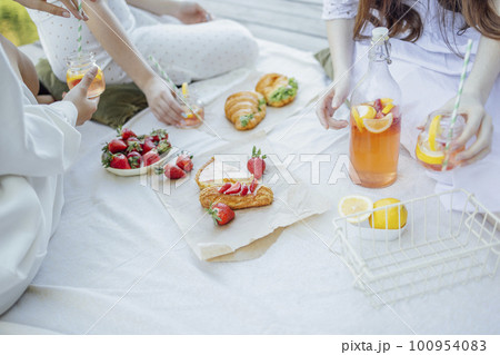 lanket with pillows and food on a wooden bridge. Bottle of strawberry and lemon smoothie 100954083