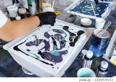 Master class on an Acrylic Fluid Pouring. Young women paint with liquid acrylic in an art workshop Master class on an Acrylic Fluid Pouring. Young women paint with liquid acrylic in an art workshop 100954531