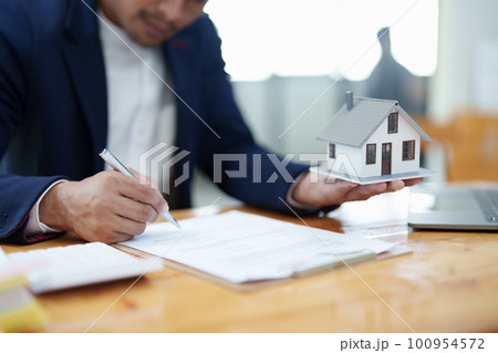 Guarantee, Mortgage, agreement, contract, Signing, Male client holding pen to reading agreement document to sign land loan with real estate agent or bank officer. Guarantee, Mortgage, agreement, contract, Signing, Male client holding pen to reading agreement document to sign land loan with real estate agent or bank officer. 100954572