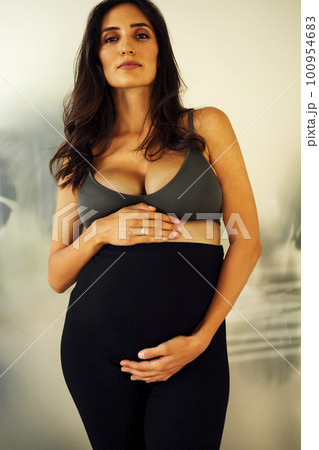 Beautiful young pregnant woman in a sports top and leggings 100954683
