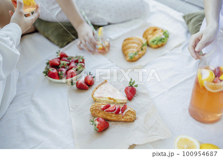lanket with pillows and food on a wooden bridge. Bottle of strawberry and lemon smoothie 100954687