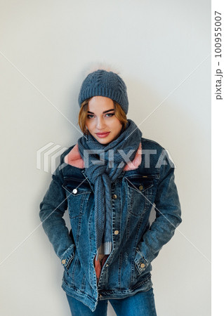 a woman with a warm hat with a scarf in winter clothes stands on a white background a woman with a warm hat with a scarf in winter clothes stands on a white background 100955007