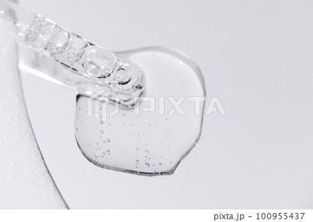 Close up of gel or serum glass pipette with transparent drops on white background 100955437