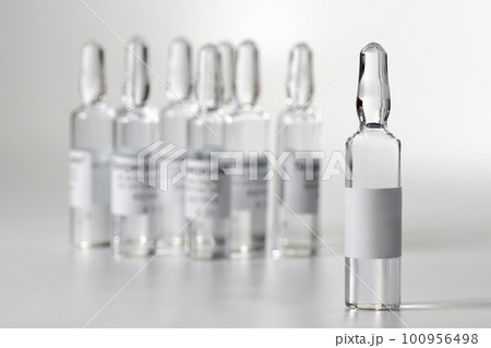 Medical ampoule with medicine, on a gray background. Vaccination and Immunization. Medical ampoule with medicine, on a gray background. Vaccination and Immunization. 100956498