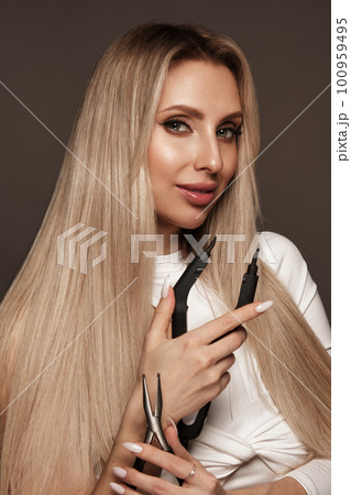 Beautiful blond girl with a perfectly hair, and classic make-up with a strand of hair for extension. Beauty face and hair. 100959495