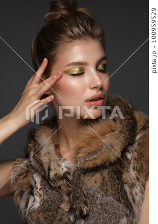 Portrait of a beautiful woman in a furcoat with creative gold makeup in a fashion style. Beauty face. Portrait of a beautiful woman in a furcoat with creative gold makeup in a fashion style. Beauty face. 100959529