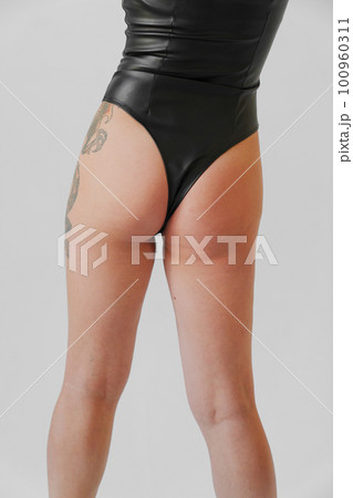 a sexy blonde with tattoos in a leather swimsuit. view from the back 100960311
