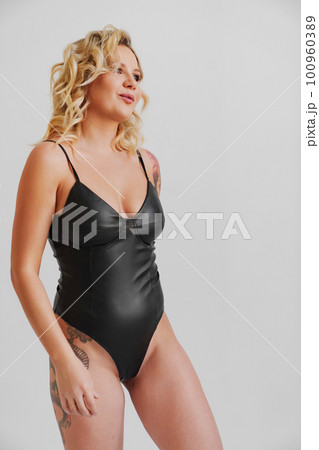 growth portrait. a sexy blonde with tattoos in a leather swimsuit 100960389