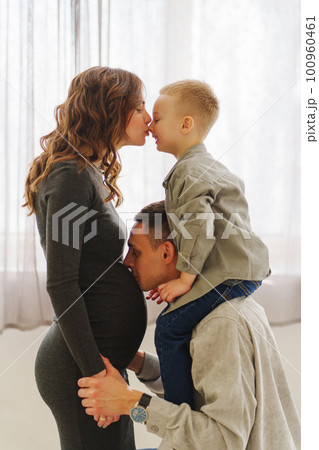 a loving and gentle family. pregnant mom, son sits on dad's shoulders. 100960461
