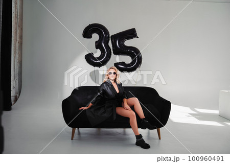 a sexy blonde in a black on the couch. balloons of numbers thirty-five 100960491