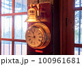 窓際で日差しを受けて輝く金色の時計 100961681