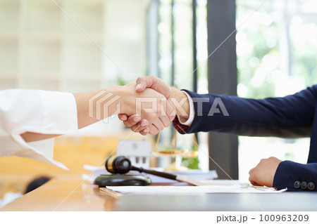 Portrait of a male lawyer shaking hands with a client to settle a court case. 100963209