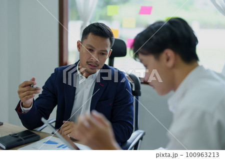 Concept of the impact of warring countries, male economists are using tablets to consult with marketing staff or accountants to adjust production and investment strategies to the current situation 100963213