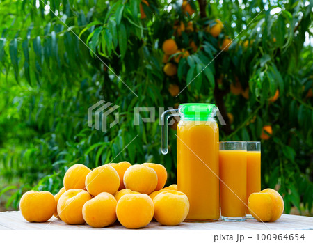 Fresh yellow peaches and juice under green tree 100964654