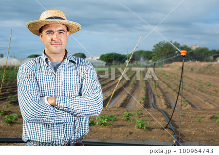Horticulturist standing in farm field with irrigation system 100964743