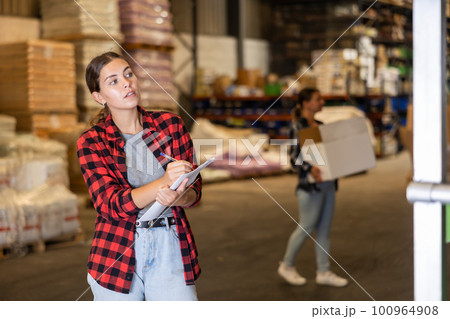 Young woman checking quantity of goods in storehouse 100964908