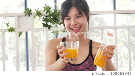 Women hands holding cold orange juice fresh fruit cool drinking. Asian women smile laugh look at camera health care home fitness lifestyle. Beautiful female pouring orange juice from cocktail bottle 100965645