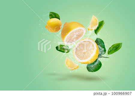Creative layout made form Lemon fruit and lemon slices and water splashing on a green background. 100966907
