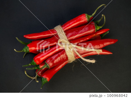 Chili pepper isolated on a black background. Knitted hot chili pepper tied with a rope. Chili hot pepper clipping path. Chili pepper isolated on a black background. Knitted hot chili pepper tied with a rope. Chili hot pepper clipping path. 100968042