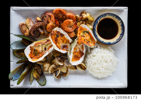 Sauteed seafood on white plate close up isolated on black background top view Sauteed seafood on white plate close up isolated on black background top view 100968173