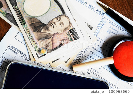 確定申告書と一万円札、ペン、印鑑、スマートフォン 確定申告書と一万円札、ペン、印鑑、スマートフォン 100968669