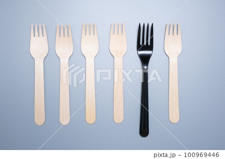 Plastic and wooden forks on a gray background. Save the ecology. Plastic and wooden forks on a gray background. Save the ecology. 100969446