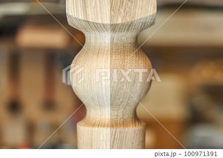 Wooden carved leg of solid oak of dining table in workshop extreme close up view 100971391