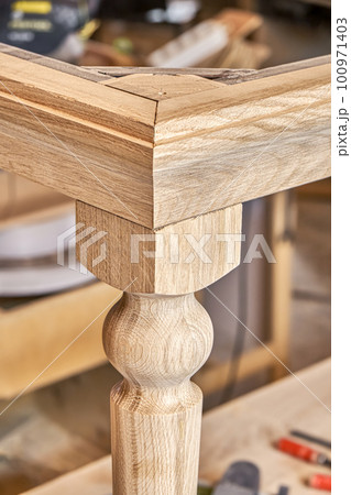 Wooden dining table with carved leg of solid oak and metal frame build process in workshop close up view Wooden dining table with carved leg of solid oak and metal frame build process in workshop close up view 100971403