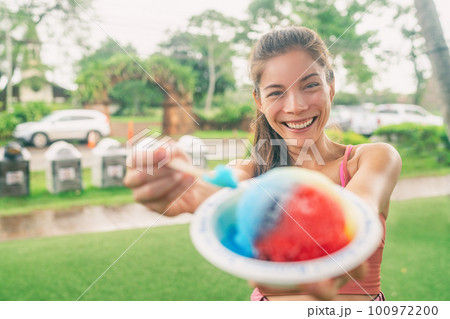 Shave Ice Hawaii Asian woman tourist eating local food hawaiian snow cone dessert food happy showing colorful ice cream treat. Shave Ice Hawaii Asian woman tourist eating local food hawaiian snow cone dessert food happy showing colorful ice cream treat. 100972200