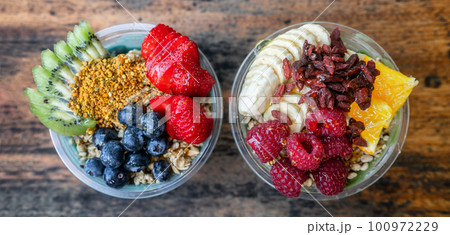 Acai bowls top view banner panoramic of healthy food breakfast smoothie bowl at restaurant. Two fruit cups filled with spirulina, kiwi, goji berries summer eating. 100972229