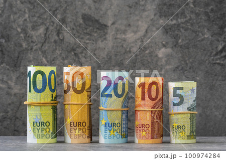 Straight row of accurately rolled hundred, fifty, twenty, ten and five paper euro banknotes Straight row of accurately rolled hundred, fifty, twenty, ten and five paper euro banknotes 100974284