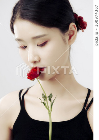 Beautiful girl holding a red persian buttercup flower and looking down Beautiful girl holding a red persian buttercup flower and looking down 100974367