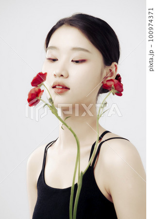 Beautiful girl with a bouquet of red persian buttercup flowers is looking down 100974371