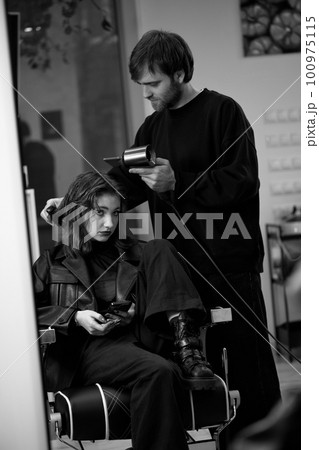 man hairdresser dries female hair with hairdryer after washing man hairdresser dries female hair with hairdryer after washing 100975115