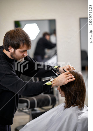 male hairdresser working with client at hair salon 100975128