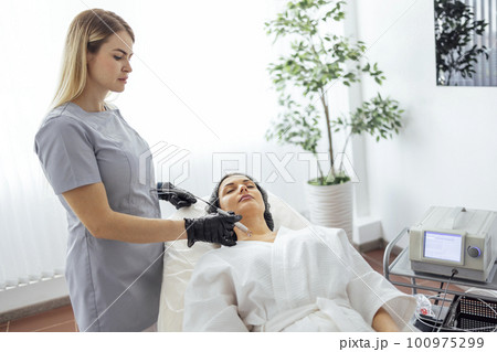 Beautiful caucasian young woman is doing a mole removal procedure in a modern beauty cosmetic dermatological clinic Beautiful caucasian young woman is doing a mole removal procedure in a modern beauty cosmetic dermatological clinic 100975299
