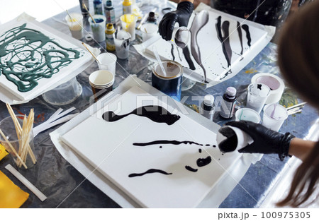 Master class on an Acrylic Fluid Pouring. Young women paint with liquid acrylic in an art workshop 100975305