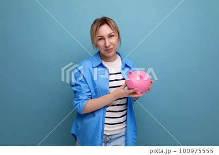 horizontal photo of attractive young woman in casual outfit cute hugging a piggy bank of coins on a 100975555