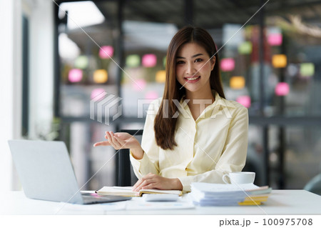 Beautiful Asian Banker or Accountant makes financial report and tax, analyzes profits. Accountant checks status of financial 100975708