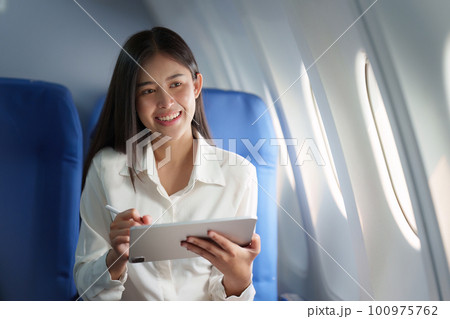 Beautiful Asian businesswoman working with digital tablet in aeroplane. working, travel, business concept 100975762