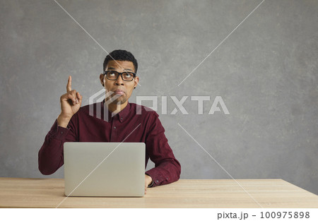 Pensive dark-skinned man who works with his laptop has found a great idea to solve the problem. Pensive dark-skinned man who works with his laptop has found a great idea to solve the problem. 100975898