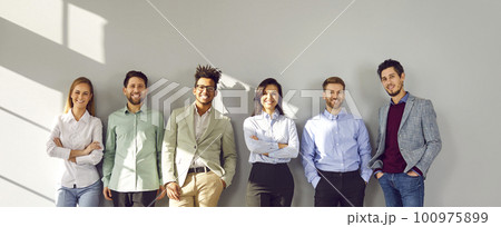 Successful smiling team of employees standing near gray wall 100975899
